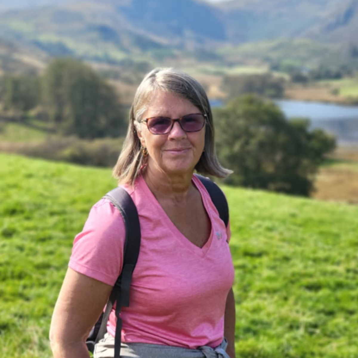 Jen standing outside on a sunny day in a green hilly landscape.
